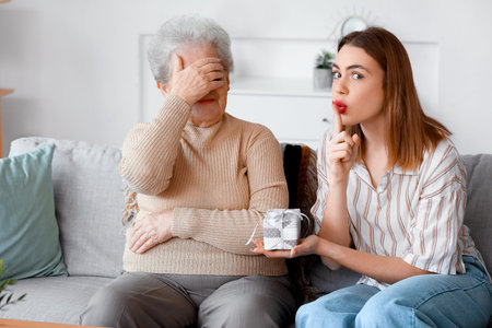 Young woman greeting her grandmother with gift at home