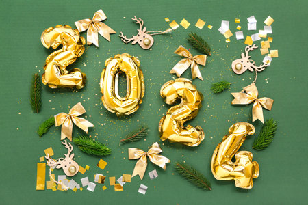 Composition with figure 2024 made of foil balloons, Christmas decorations and fir branches on green backgroundの写真素材