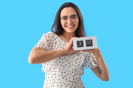 Young woman with clock on blue background. Deadline concept