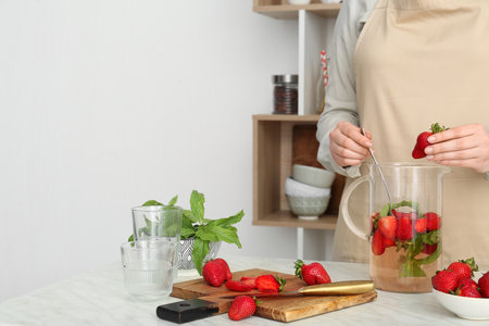 Woman preparing strawberry lemonade in kitchenの写真素材