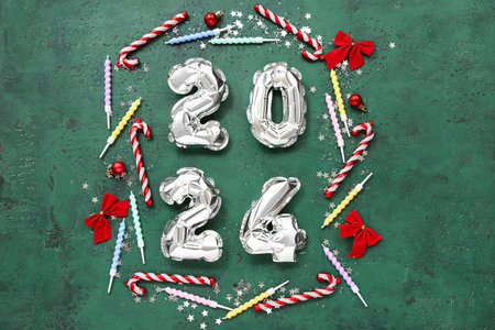 Composition with figure 2024 made of foil balloons, Christmas decorations, candles and confetti on...
