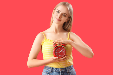 Young woman with alarm clock on red background. Deadline concept