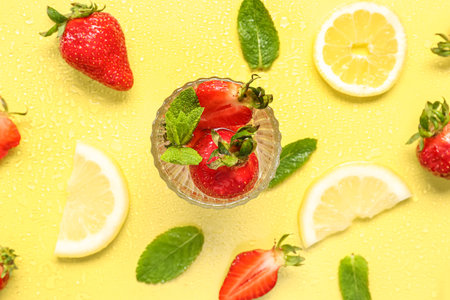 Glass of fresh lemonade with strawberry and lemon on yellow backgroundの写真素材