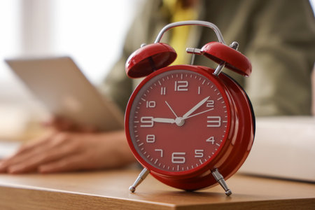 Alarm clock on table of businesswoman in office, closeupの写真素材