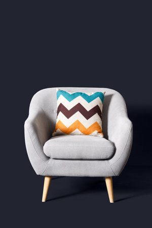 Cozy gray armchair with cushion on black backgroundの写真素材