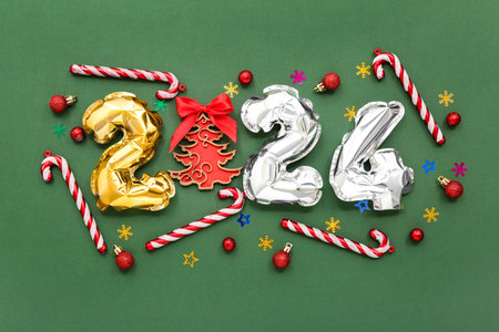 Composition with figure 2024 made of foil balloons and Christmas decorations on green backgroundの写真素材