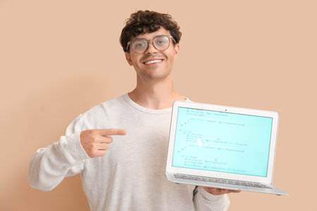 Male programmer pointing at laptop on beige backgroundの写真素材