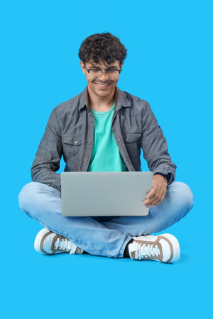 Male programmer working with laptop on blue backgroundの写真素材