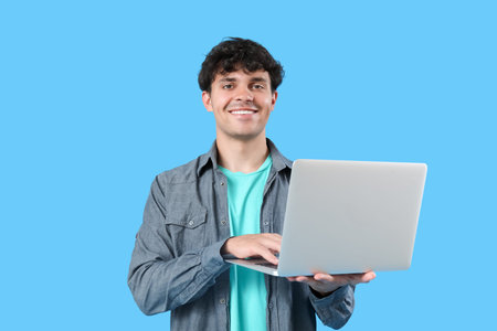 Male programmer working with laptop on blue background