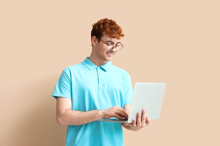 Male programmer working with laptop on beige backgroundの写真素材