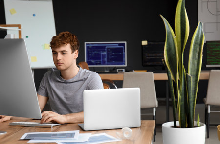 Male programmer working with computer at table in officeの写真素材