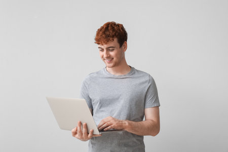 Male programmer working with laptop on light backgroundの写真素材