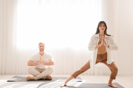 Sporty young couple practicing yoga in light living roomの写真素材