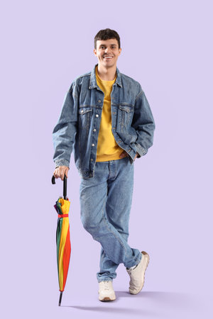 Young man with umbrella on lilac backgroundの写真素材