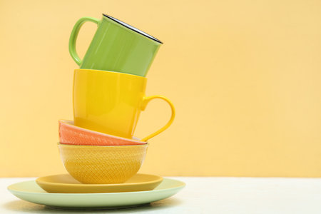 Set of clean plates and cups on table against yellow backgroundの写真素材