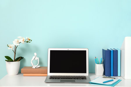 Modern workplace with laptop, houseplant and books in light officeの写真素材