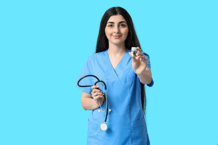 Beautiful young female doctor with stethoscope and pills on blue backgroundの写真素材