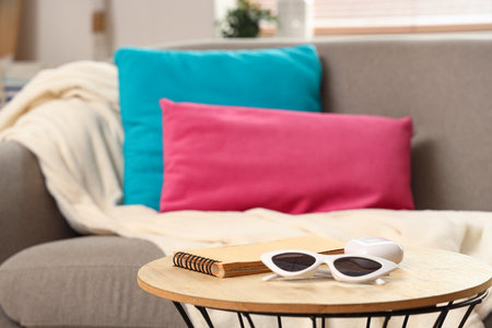 Cozy sofa with pillows and coffee table with sunglasses in living room, closeupの写真素材
