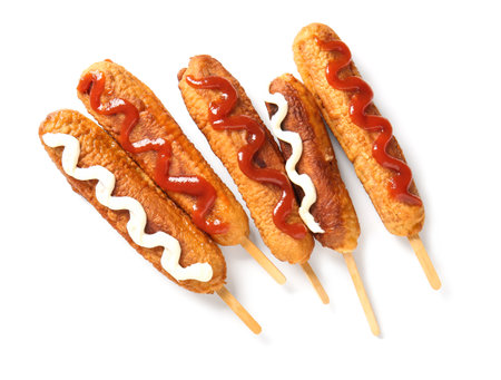 Tasty corn dogs with mayonnaise and ketchup on white backgroundの写真素材