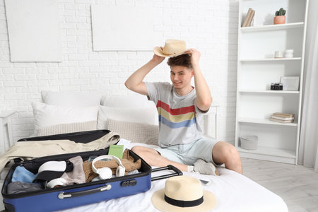 Male tourist unpacking suitcase on bed in hotel roomの写真素材