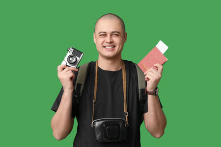 Young male tourist with photo camera and passport on green background
