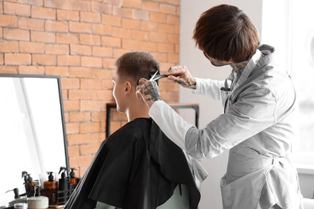 Male tattooed hairdresser cutting client's hair in barbershopの写真素材