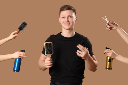Young barber and hands with hairdressing tools on brown backgroundの写真素材