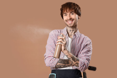 Tattooed barber with hair spray on brown backgroundの写真素材