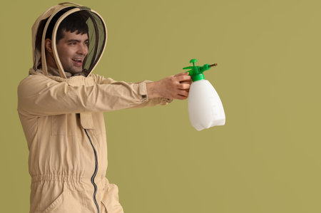 Male beekeeper with sprayer on green backgroundの写真素材