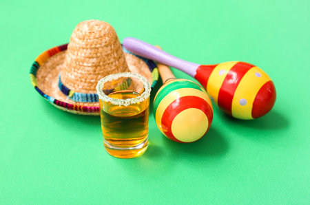 Maracas, decorative sombrero hat and shot of tequila with salt on green backgroundの写真素材