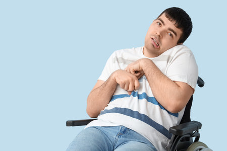 Young man in wheelchair on blue background. National Cerebral Palsy Awareness Monthの写真素材