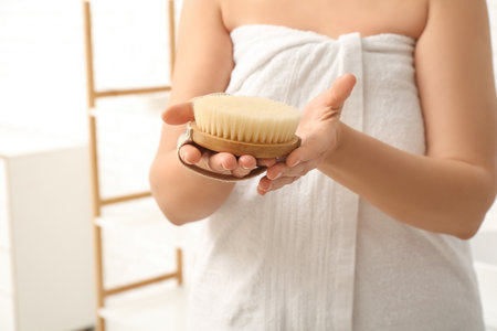 Young woman with body massage brush in bathroomの写真素材