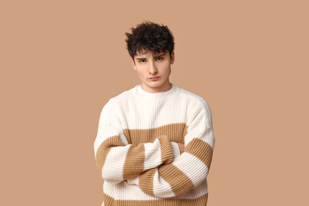 Handsome young man in stylish sweater on brown backgroundの写真素材