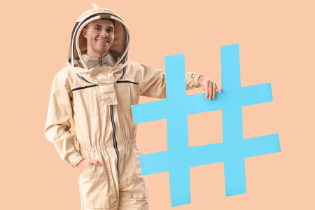 Male beekeeper in protective clothing with hashtag sign on color backgroundの写真素材