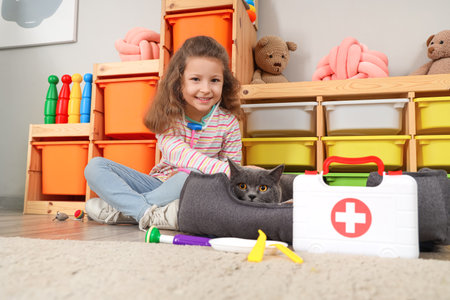 Cute little girl with British cat and first aid kit at homeの写真素材