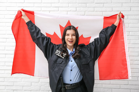 Female police officer with flag of Canada on white brick backgroundの写真素材