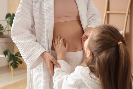 Little girl touching belly of her pregnant mother in bathroom, closeupの写真素材