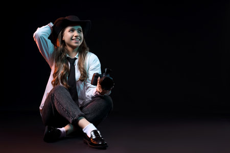 Portrait of stylish female photographer with modern camera on black backgroundの写真素材