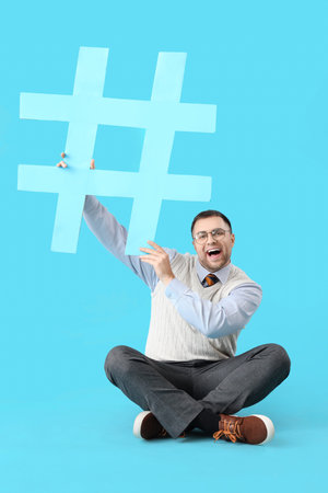 Male office worker with hashtag sitting on blue backgroundの写真素材