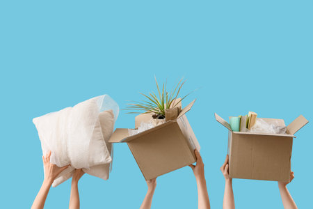 Women with moving boxes and pillows on blue background