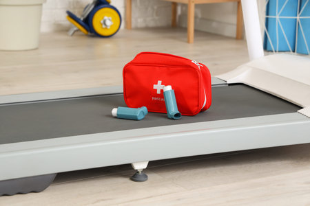 Asthma inhalers with first aid kit on treadmill in gym, closeup