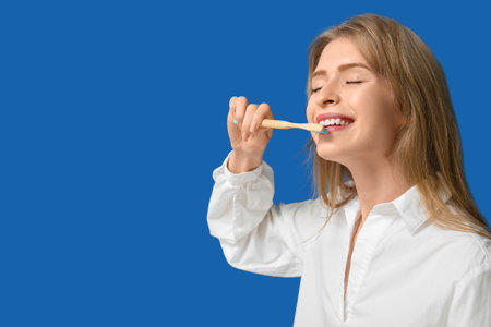 Young woman brushing her teeth on blue backgroundの写真素材