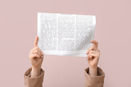 Female hands with newspaper on pink backgroundの写真素材