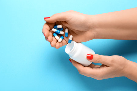 Female hands and bottle with pills on blue backgroundの写真素材