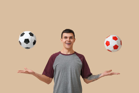 Young man with soccer balls on beige backgroundの写真素材