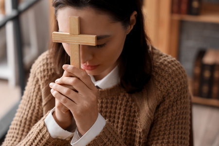 Young woman with cross praying in library, closeupの写真素材