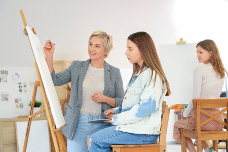 Female art teacher helping student to draw on canvas at schoolの写真素材