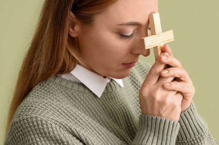 Mature woman with cross praying on green background, closeupの写真素材