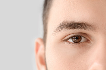 Young man with brown eyes on gray background, closeupの写真素材