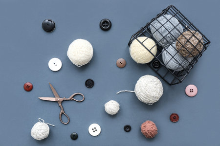 Yarn balls, scissors and buttons on blue background